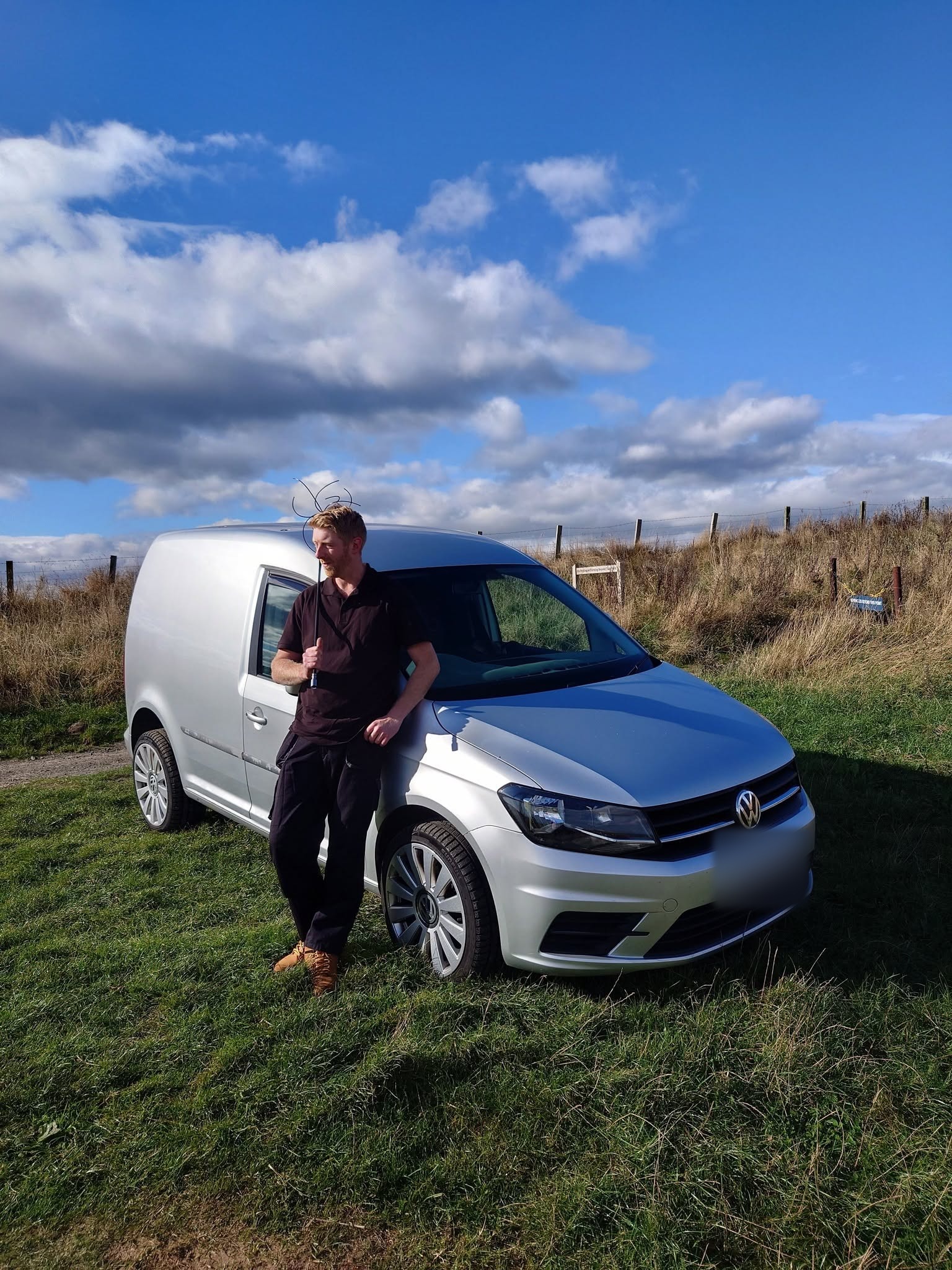 Arran leaning on his silver Northumbria & City Chimney Sweep van on the moor