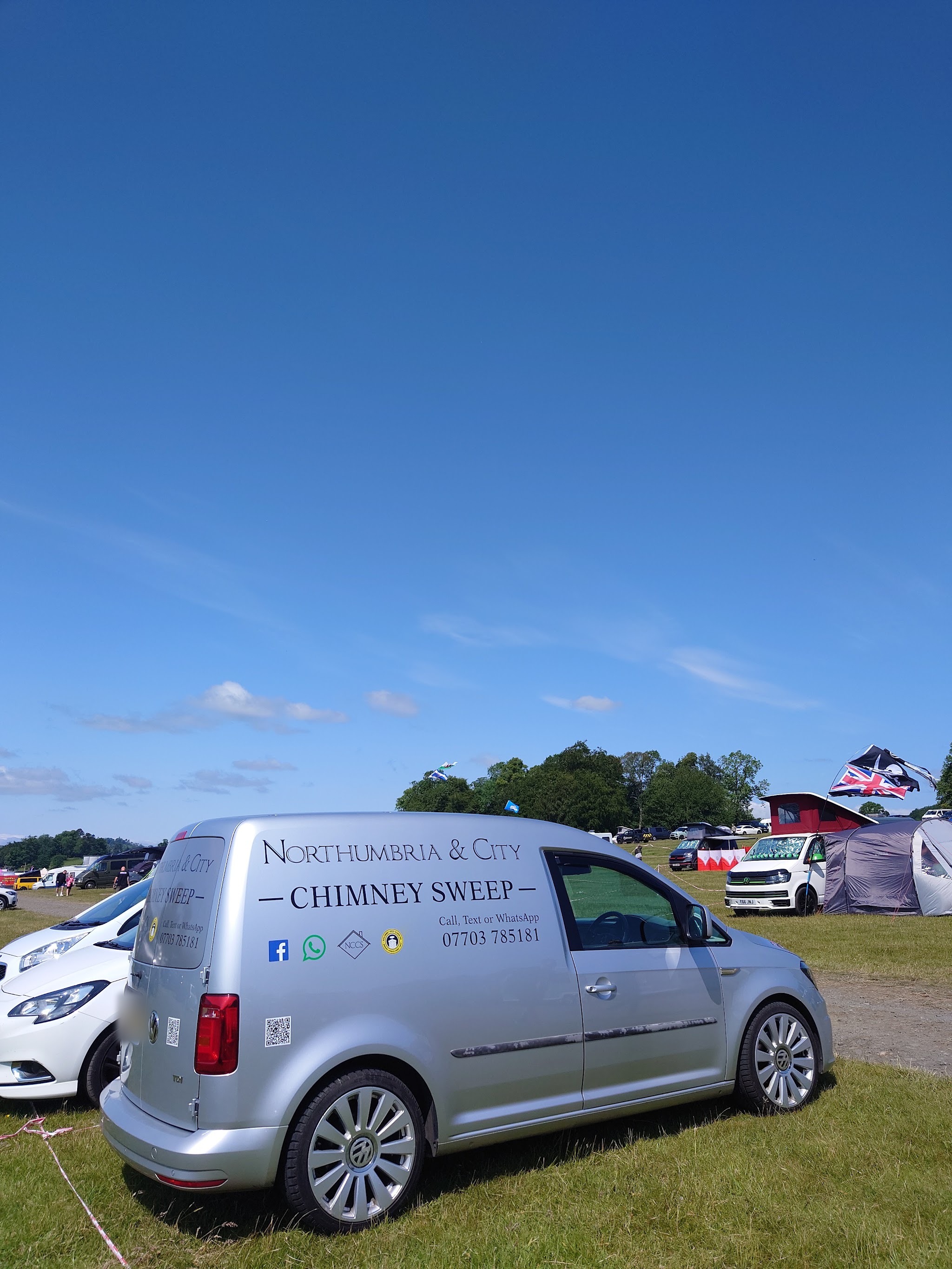 The silver Northumbria & City Chimney Sweep van parked on a show field, with Call, Text or WhatsApp 07703 785181 on the side