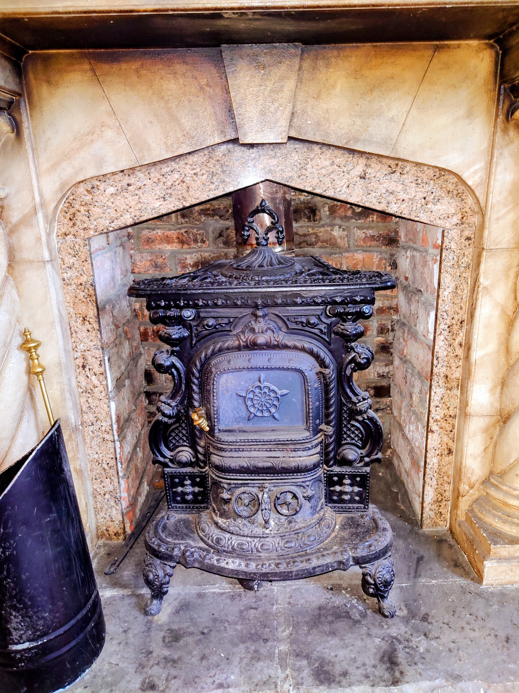 An ornate Victorian-style cast-iron stove in a marble fireplace surround