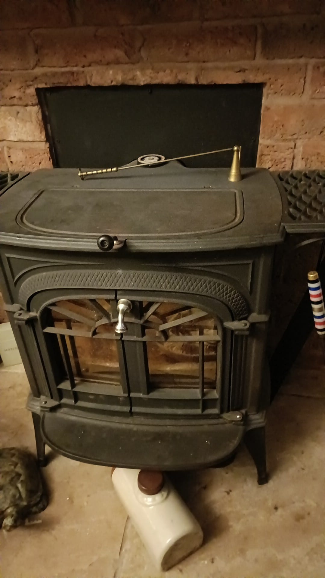 A green enamel cast-iron stove standing in a brick fireplace