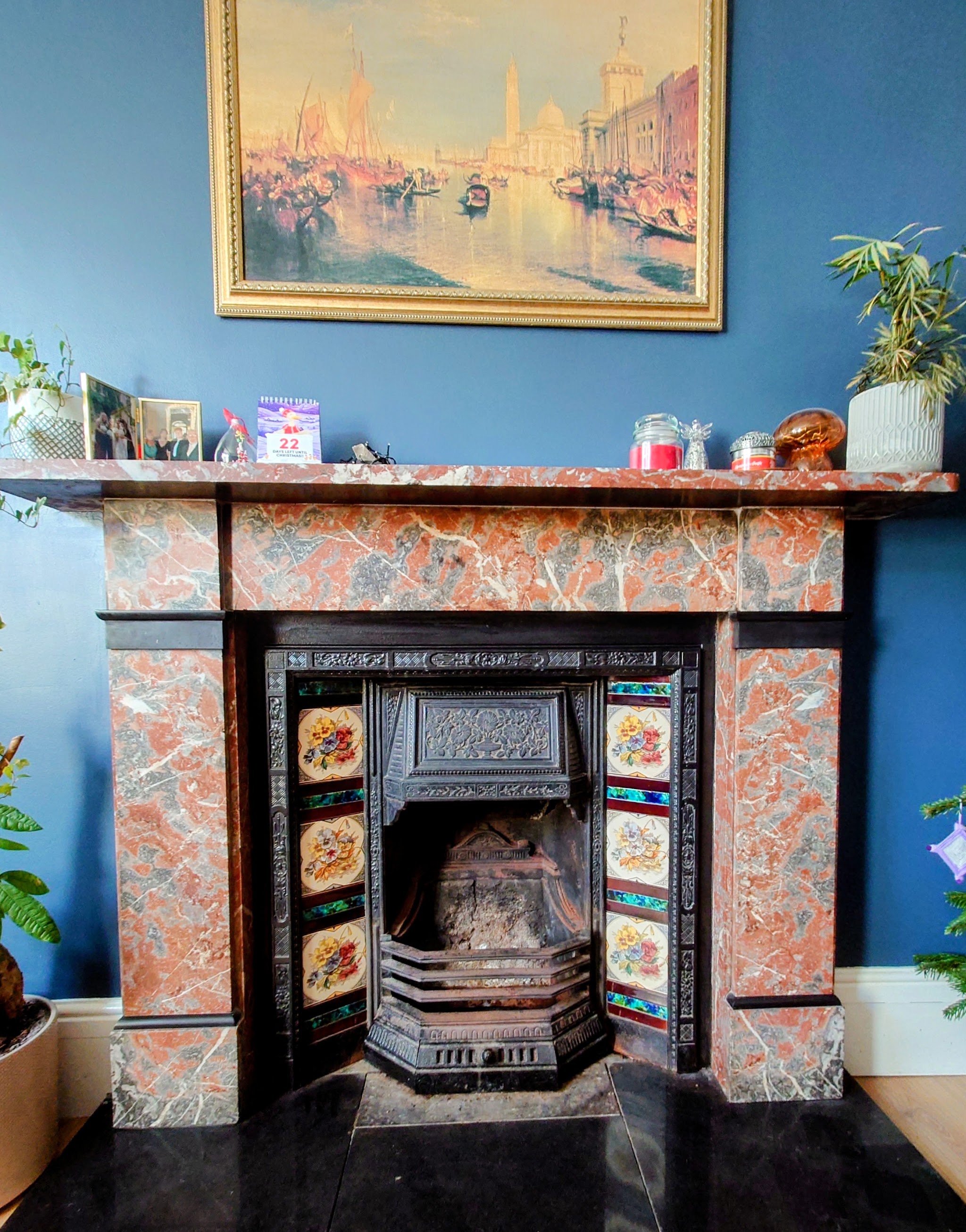 A Victorian tiled cast-iron fireplace in a red marble surround against a blue wall